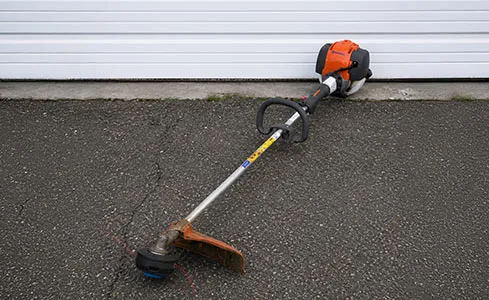String Trimmer - Gas-powered trimmer on asphalt driveway