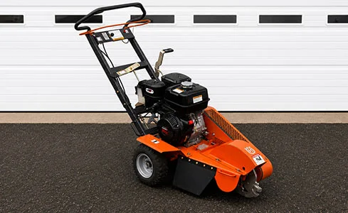 Stump Grinder - Stump grinder on asphalt with garage backdrop